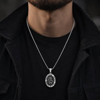Collier Saint Christophe Protecteur en acier inoxydable porté par un homme en tenue noire avec veste sombre.