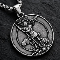 Gros plan du motif du Collier Saint Michel Protecteur en acier inoxydable sur fond anthracite texturé ardoise sombre