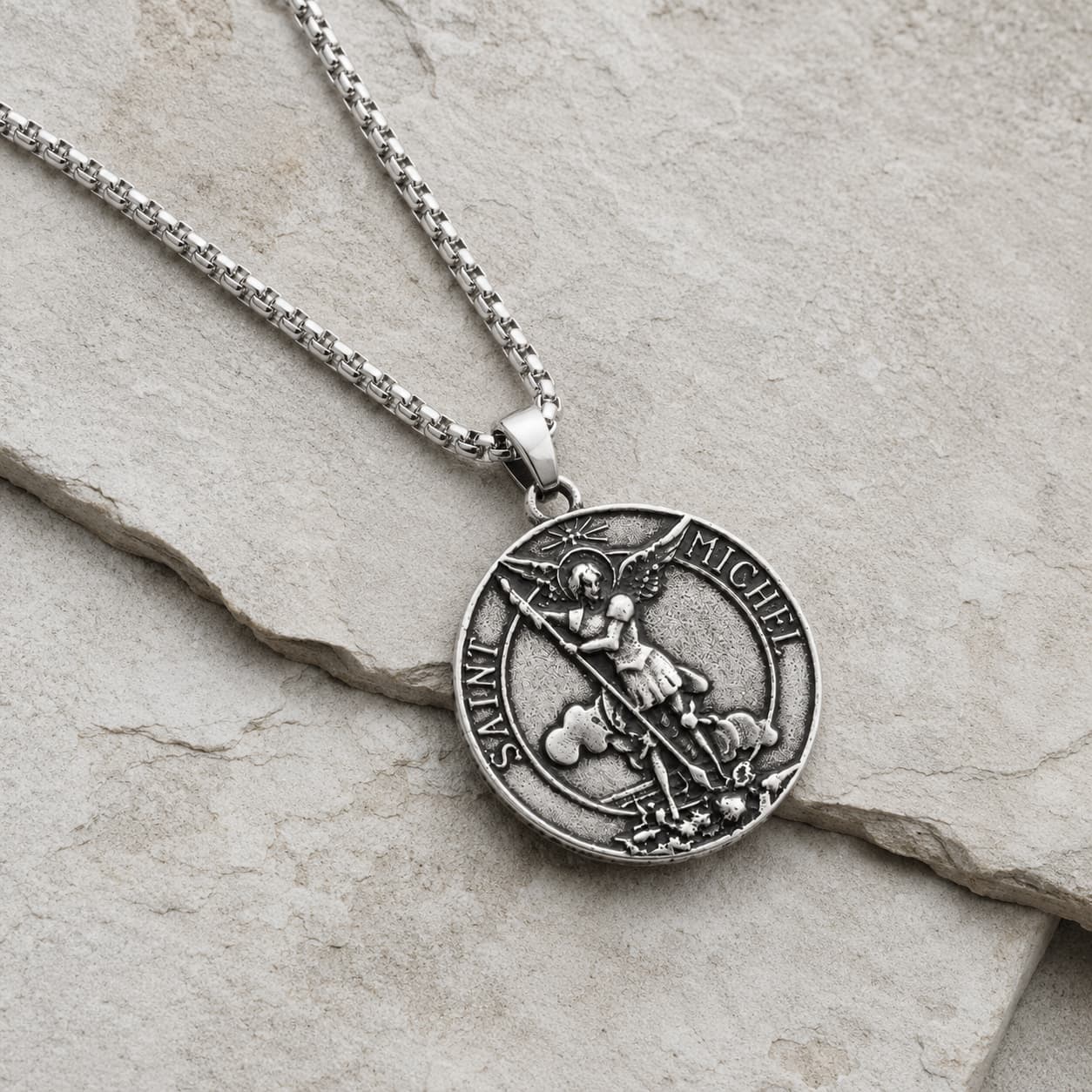 Collier Saint Michel Protecteur en acier inoxydable vue angle 3 4 sur pierre médiévale claire beige gris
