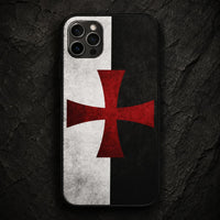 Coque iPhone Croix Templier en silicone avec croix rouge sur motif noir et blanc, posée sur pierre sombre.