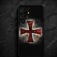 Coque Samsung Croix Templier en silicone noire avec croix rouge effet usé sur fond de pierre sombre.