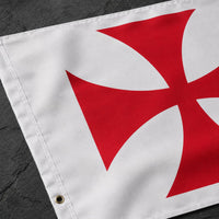 Gros plan sur la croix pattée rouge et la texture du tissu du drapeau blanc en polyester.