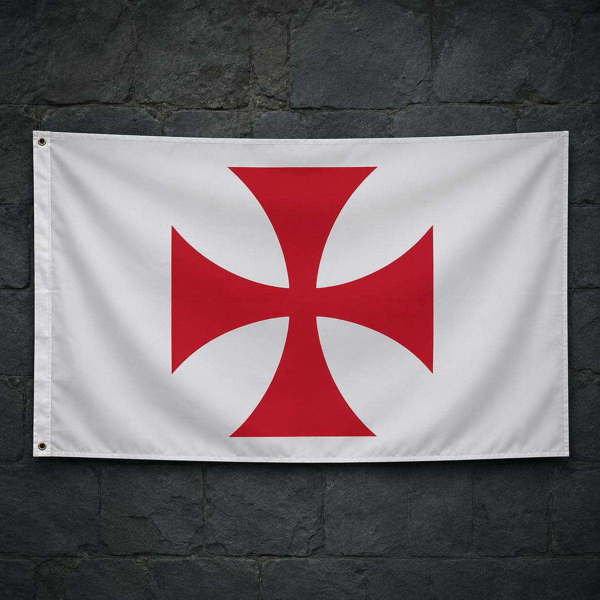 Drapeau blanc à croix pattée rouge en polyester accroché sur un mur de pierre sombre médiéval.