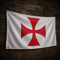 Drapeau blanc à croix pattée rouge en polyester suspendu sur un fond de bois ancien sombre.