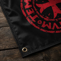 Détail du Drapeau Sigillum Templi en polyester avec œillet métallique, couture noire et texture du tissu sur bois ancien.