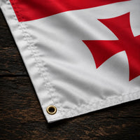 Détail du coin du Drapeau Templier Blanc aux Cinq Croix en polyester avec œillet métallique et couture visible sur le tissu.