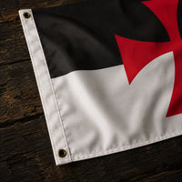 Détail des œillets et des finitions du Drapeau Templier Croix Pattée en polyester sur fond en bois ancien.