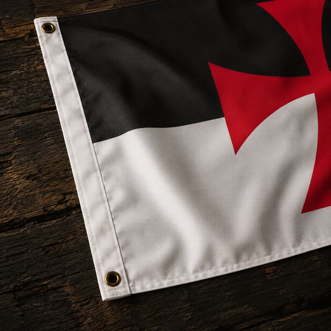 Détail des œillets et des finitions du Drapeau Templier Croix Pattée en polyester sur fond en bois ancien.