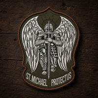 Variante vert militaire de l'Écusson de l'Archange Protecteur en tissu brodé sur fond bois ancien.