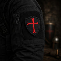 Écusson Chevalier Croisé en tissu brodé fixé sur une veste sombre dans une ambiance médiévale.