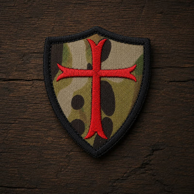 Variante camouflage de l’Écusson Chevalier Croisé en tissu brodé sur fond en bois ancien sombre.