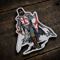 Écusson Chevalier Templier en tissu brodé en vue inclinée sur bois ancien sombre, avec bordure et relief visibles.