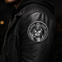 Écusson Deus Vult du Croisé en tissu brodé résistant porté sur un blouson en cuir noir dans une ambiance sombre.