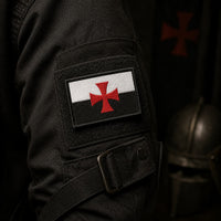Ecusson du Devoir en tissu brodé fixé sur une veste sombre dans une ambiance médiévale.