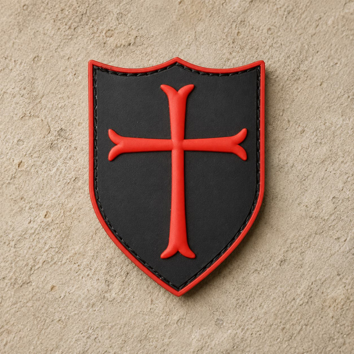 Écusson du Templier Royal en PVC noir avec croix rouge sur fond de pierre claire.
