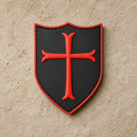 Écusson du Templier Royal en PVC noir avec croix rouge sur fond de pierre claire.