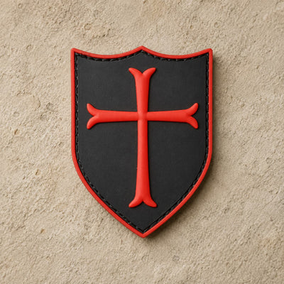 Écusson du Templier Royal en PVC noir avec croix rouge sur fond de pierre claire.