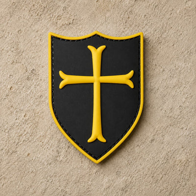 Écusson du Templier Royal en PVC noir avec croix jaune et bordure dorée sur fond de pierre claire.