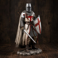 Figurine chevalier templier en résine vue en angle avec cape, épée et bouclier dans un décor bois ancien.