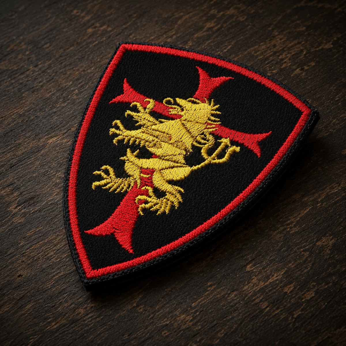 Patch Écusson Coeur du Templier en tissu brodé en vue légèrement inclinée sur bois ancien sombre.