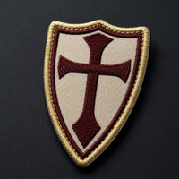 Gros plan sur la broderie de la croix bordeaux et de la bordure dorée du patch Écusson de la Lance du Templier.