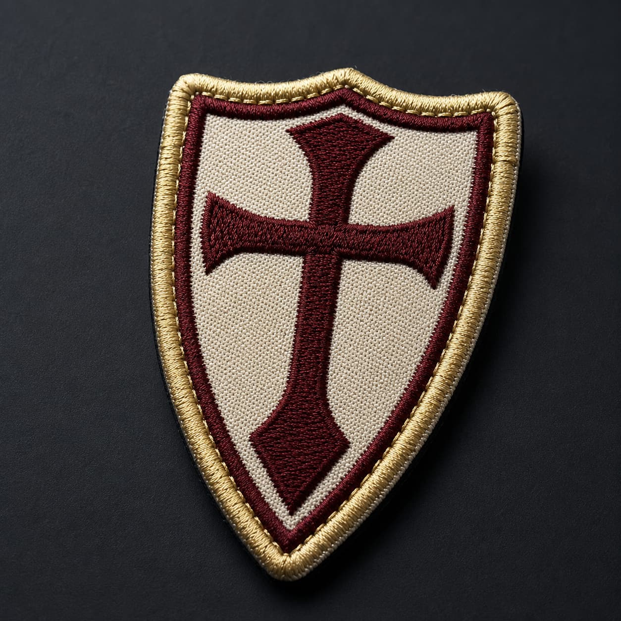 Gros plan sur la broderie de la croix bordeaux et de la bordure dorée du patch Écusson de la Lance du Templier.