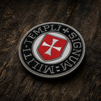 Patch Écusson du Sceau Templi en tissu brodé présenté en vue inclinée sur un fond en bois ancien sombre.
