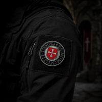Patch Écusson du Sceau Templi en tissu brodé fixé sur une veste sombre dans une ambiance médiévale.