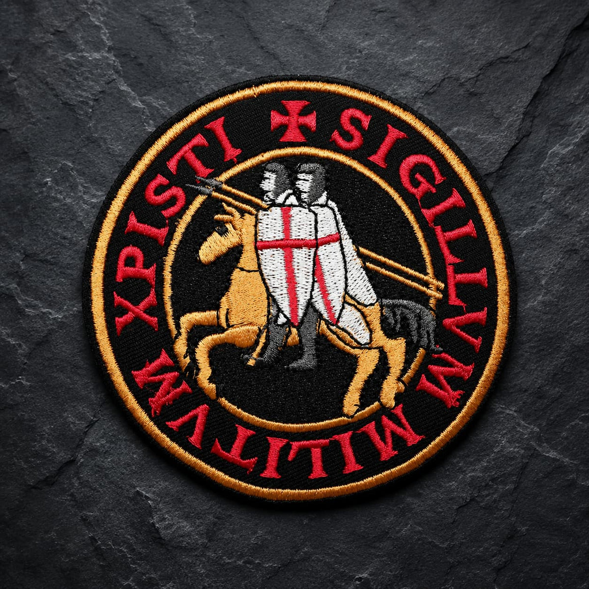 Patch Écusson de l’Exécuteur en tissu brodé avec croix noire et trois crânes sur fond de pierre sombre.