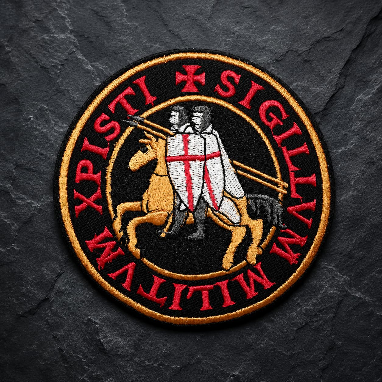 Patch Écusson de l’Exécuteur en tissu brodé avec croix noire et trois crânes sur fond de pierre sombre.