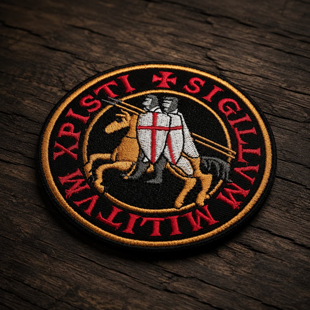 Patch Écusson de l’Exécuteur en tissu brodé présenté en vue inclinée sur un fond en bois ancien sombre.