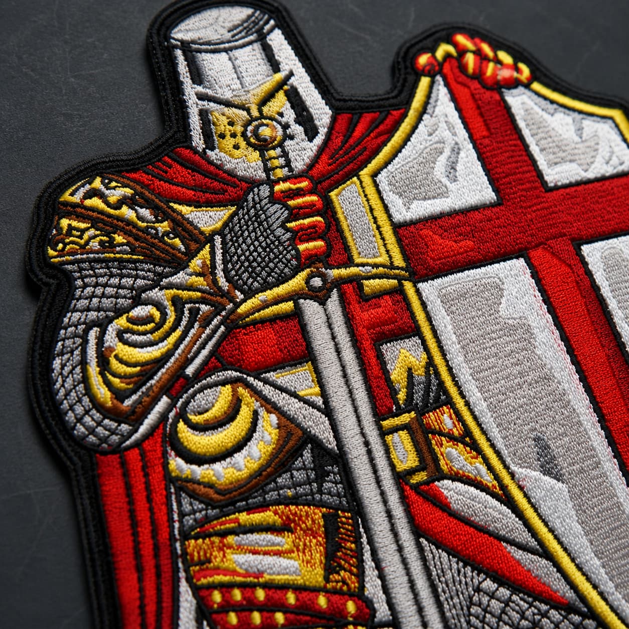 Gros plan sur la broderie du chevalier, de l’épée et du bouclier du patch Écusson prière du Templier.