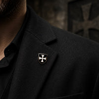 Pin’s Bouclier du Temple en alliage métallique porté sur une veste noire dans une ambiance médiévale sombre.