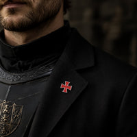 Pin’s Croix du Temple en alliage métallique porté sur une veste noire dans une ambiance médiévale sombre.