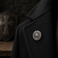 Pin's du Chevalier Templier en cuivre porté sur une veste noire dans une ambiance médiévale sombre.