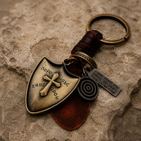 Porte-clé de l'Aventurier Croisé en alliage métallique et simili cuir en vue légèrement inclinée sur pierre texturée.