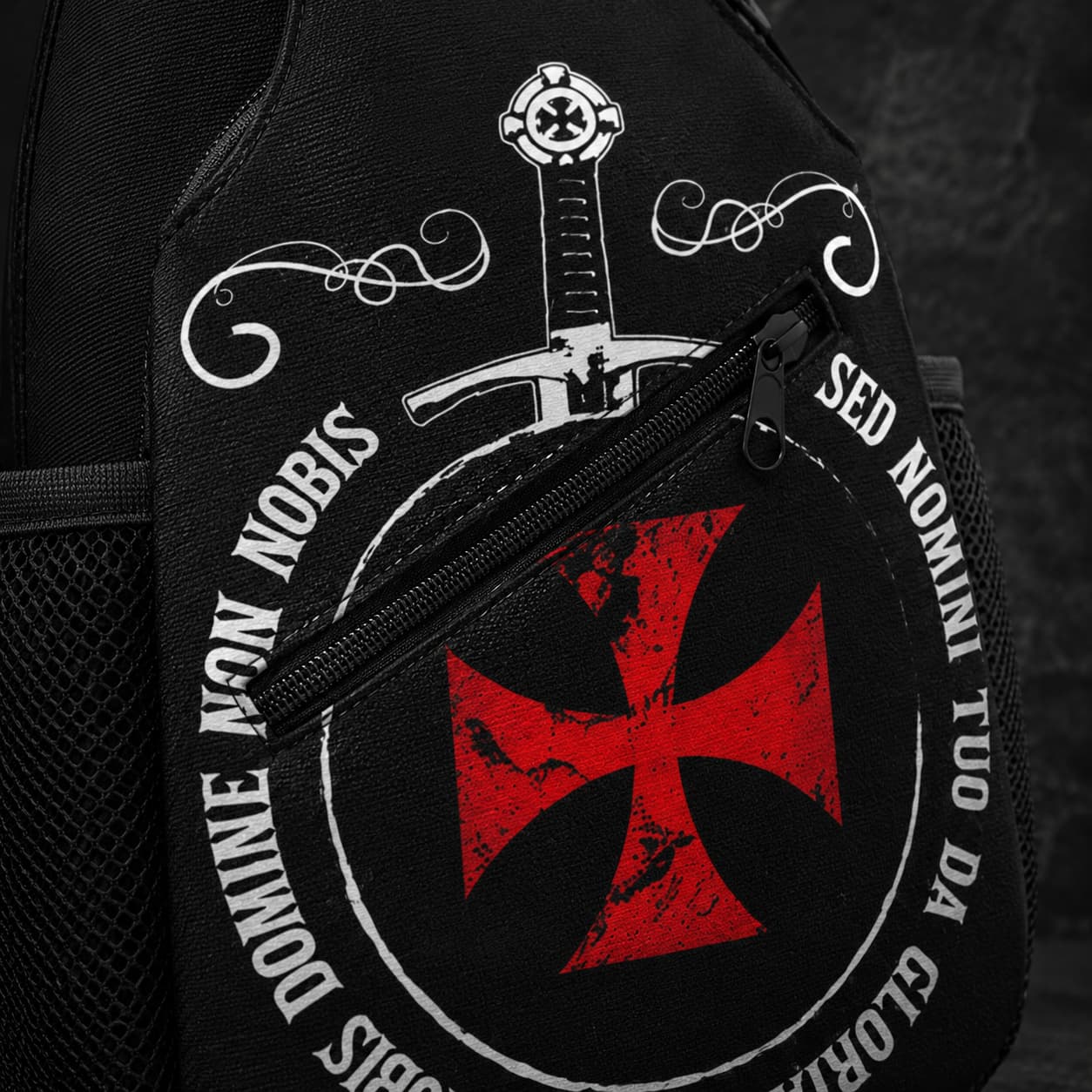 Gros plan du Sac à bandoulière Non Nobis en polyester avec croix rouge, épée blanche, fermeture zippée et tissu noir texturé.