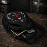 Sac à bandoulière Non Nobis en polyester ouvert sur bois ancien avec téléphone, carnet et accessoires rangés à l’intérieur.