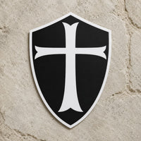 Sticker du Chevalier Templier en vinyle résistant présenté de face sur pierre claire, avec bouclier noir et croix blanche.