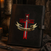 Sticker du Gardien de la Foi en vinyle adhésif appliqué sur un carnet en cuir noir dans une ambiance médiévale sombre.