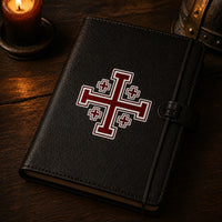 Sticker de l’Ordre de Saint Sépulcre en vinyle adhésif appliqué sur un carnet en cuir noir dans une ambiance médiévale sombre.