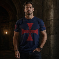 Homme viril portant le T-Shirt Croix des Chevaliers du Temple bleu marine dans un décor médiéval en pierre.