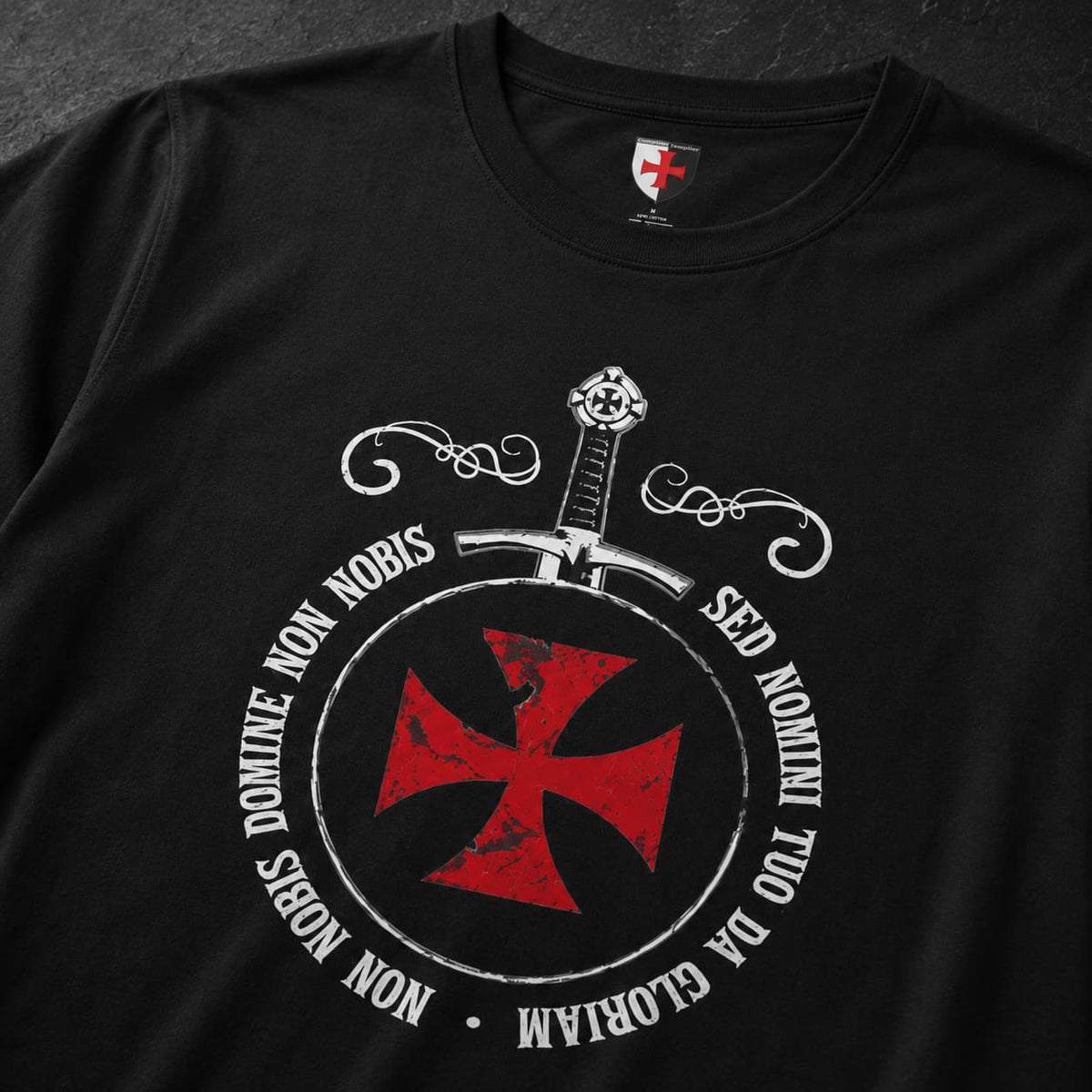 Gros plan du motif du T-Shirt Sceau des Croisés en coton noir avec croix rouge, épée et devise circulaire.