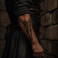 Tatouage Prière d’Archange porté sur l’avant-bras d’un homme en tenue sombre dans une ambiance médiévale.