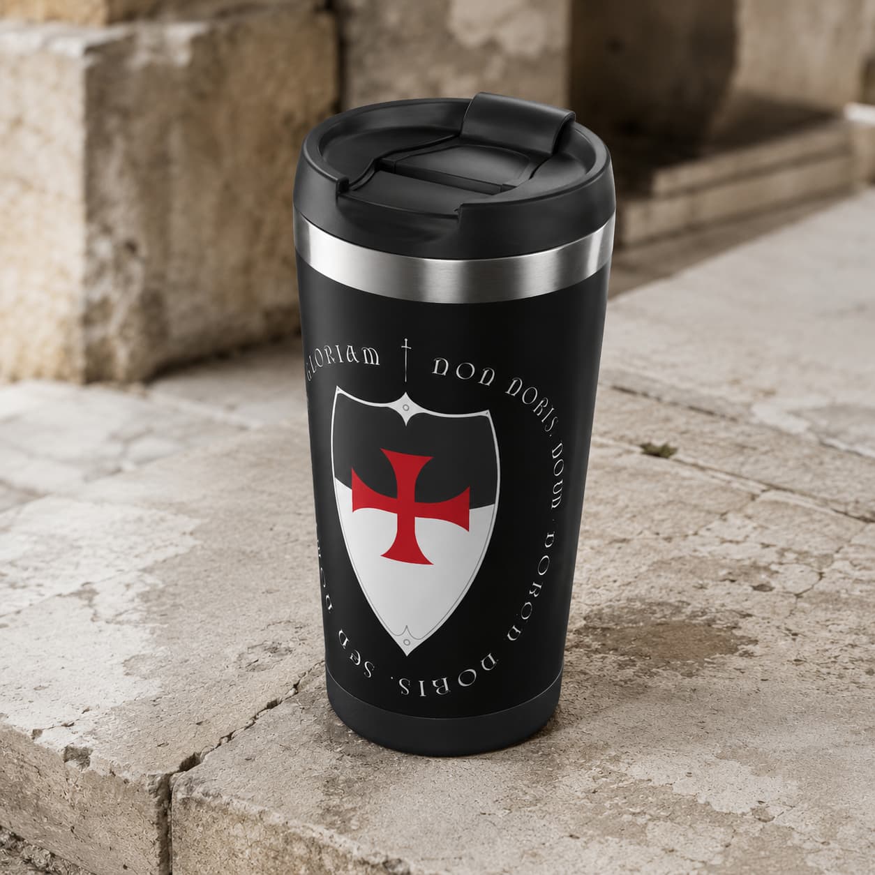 Thermos du Temple en acier inoxydable noir vu en angle sur pierre claire avec couvercle et bord inox visibles.
